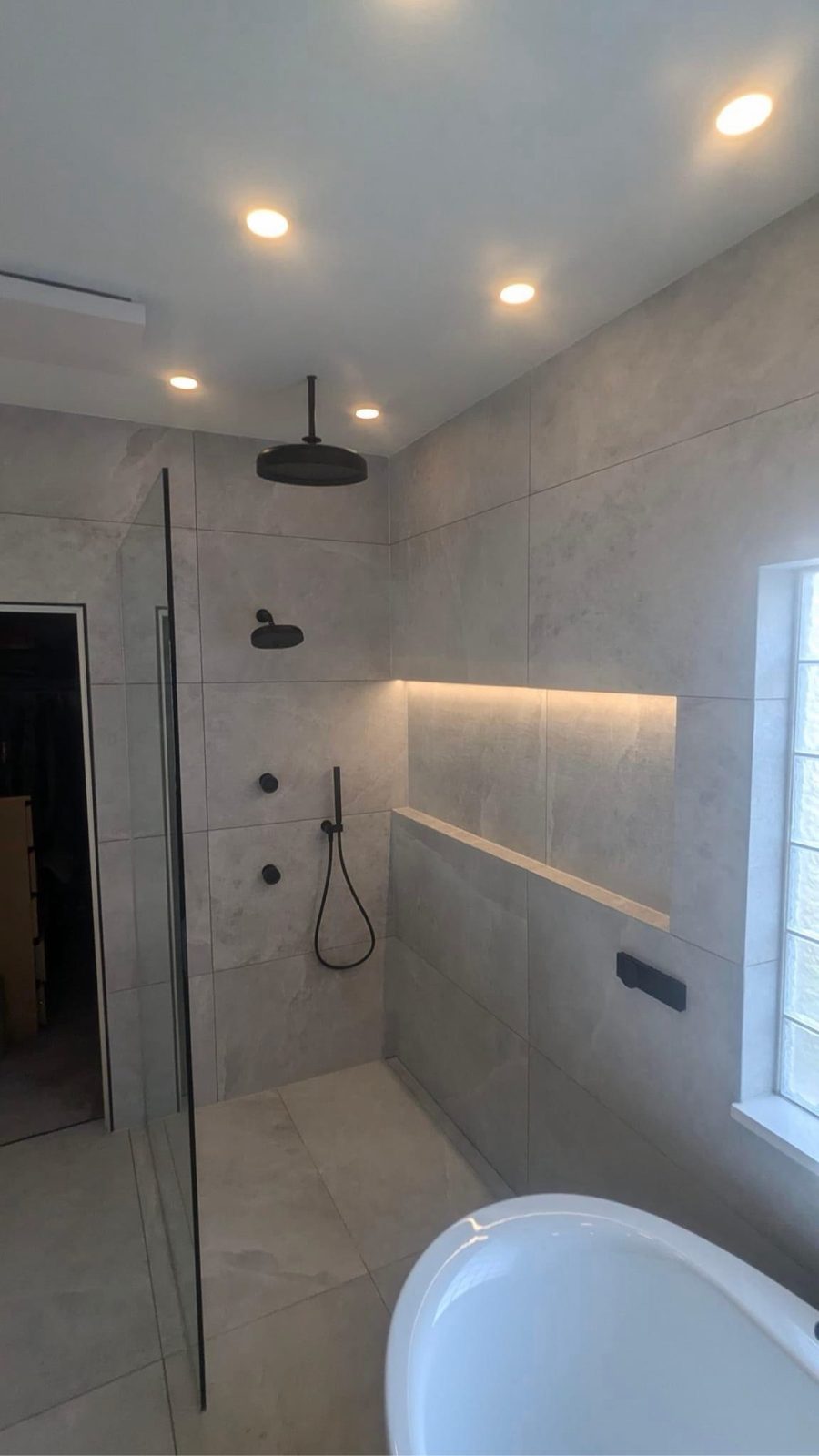 Walk-in shower with large-format tile and matte black rain shower head