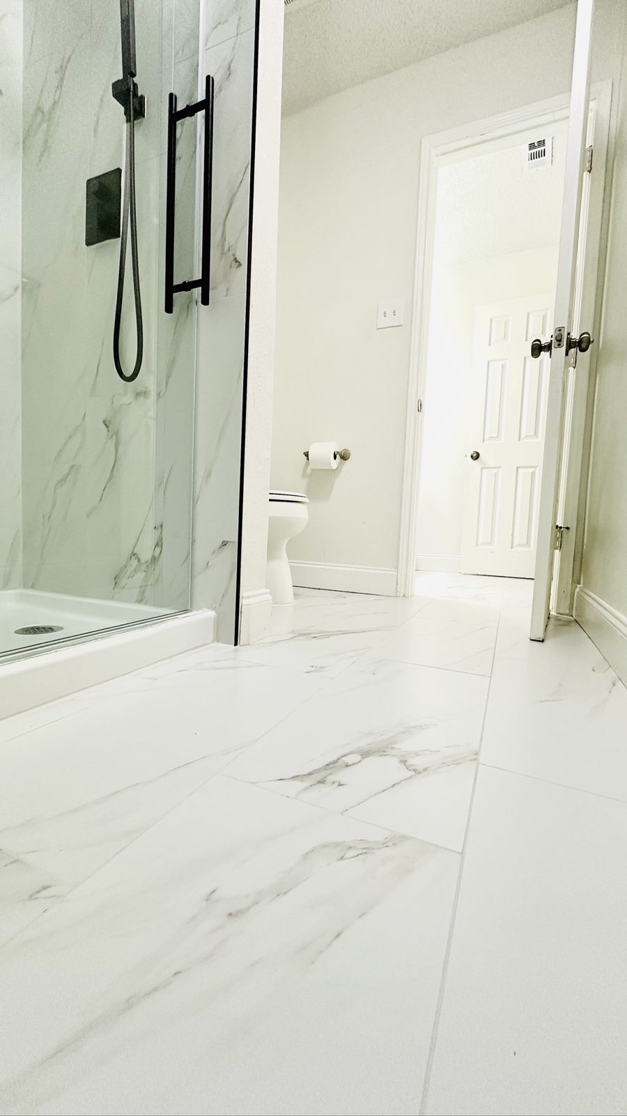 Wide view of a remodeled bathroom with marble-look tile flooring