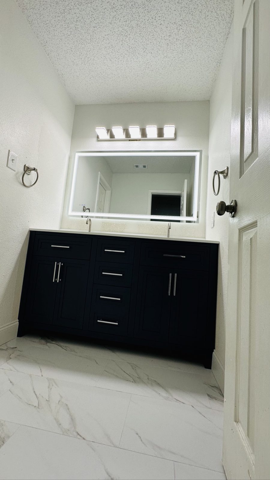 Double vanity with lighted mirror seen from the bathroom doorway