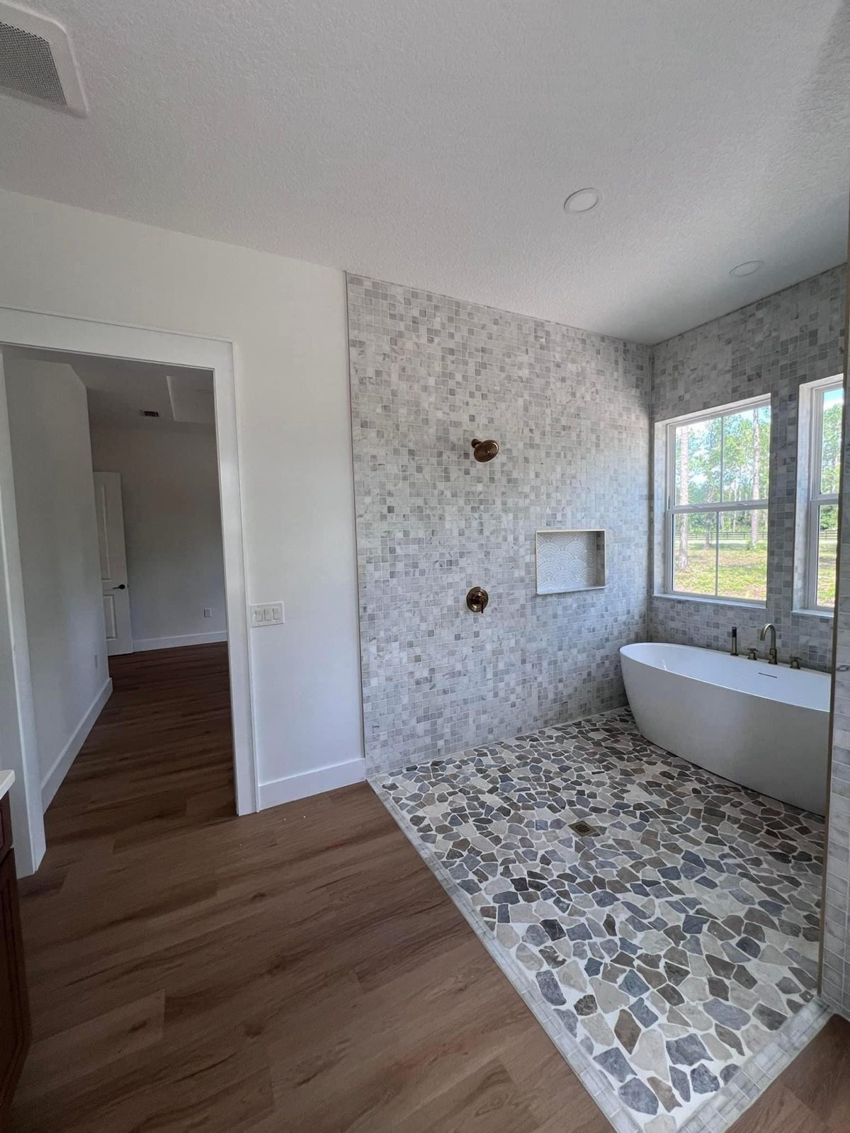 Curbless walk-in wet room with stone-look floor and freestanding tub